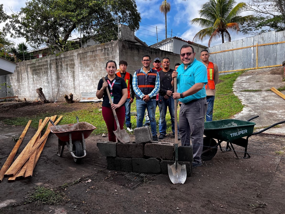 •	Del lado derecho: hombre con camisa azul cielo, pantalón gris, lentes negros y pala en mano, Erick Romero (Director Nacional de Aldeas Infantiles SOS en Honduras). •	Del lado izquierdo: mujer con camisa negra, pantalón rojo y pala en mano, Zendy Talaver